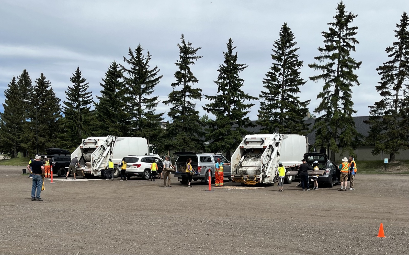 Two white City of Calgary trucks parked at the event; volunteers in yellow vests standing between them.