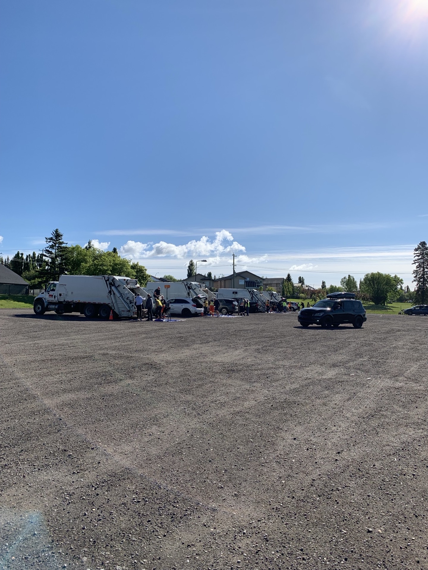 Wider view of the cleanup lot — two City garbage trucks side by side, volunteers working between them, the day in full swing.