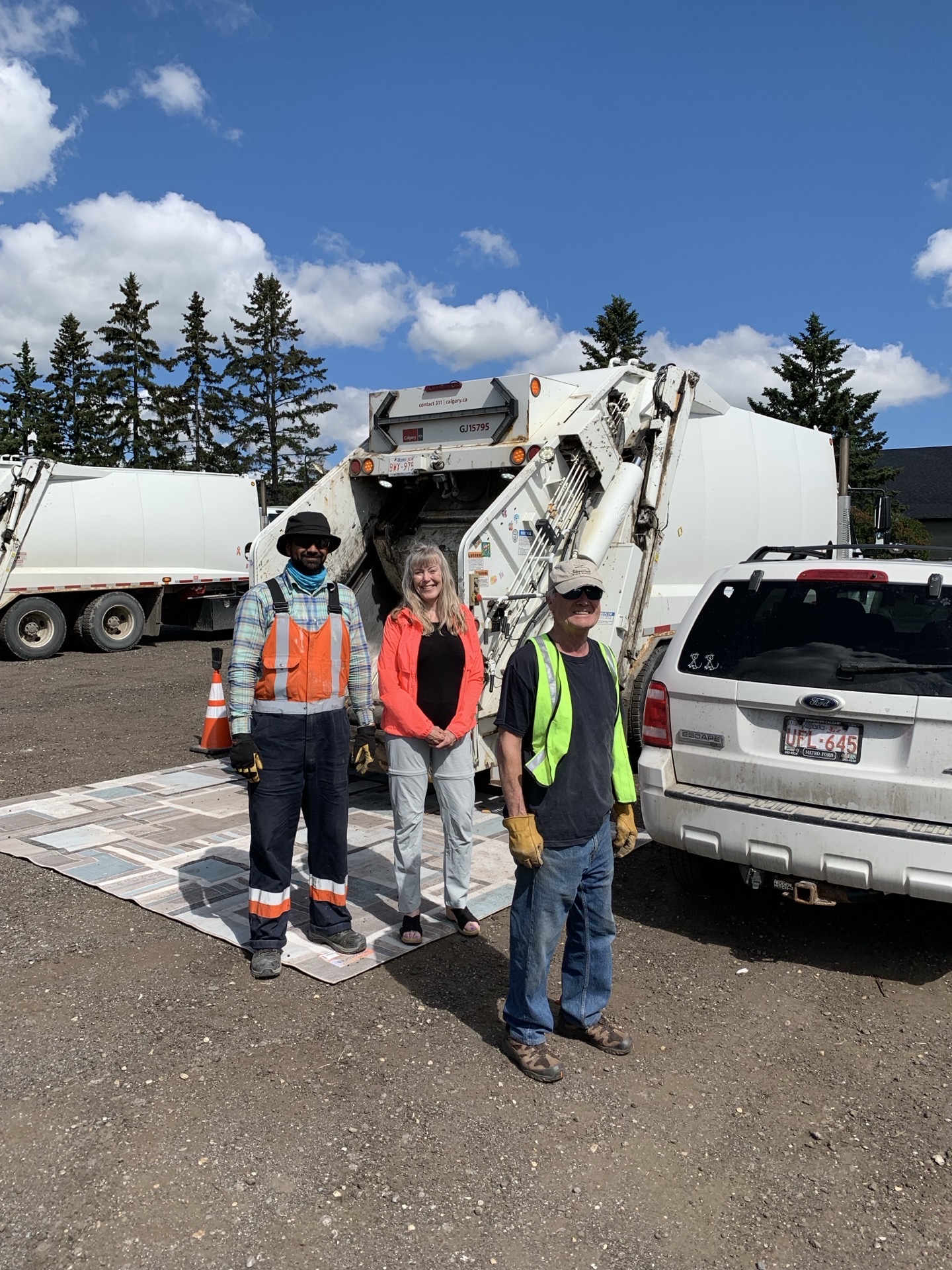 Three volunteers — one in orange coveralls — posed in front of the truck with the blue donation tarp.