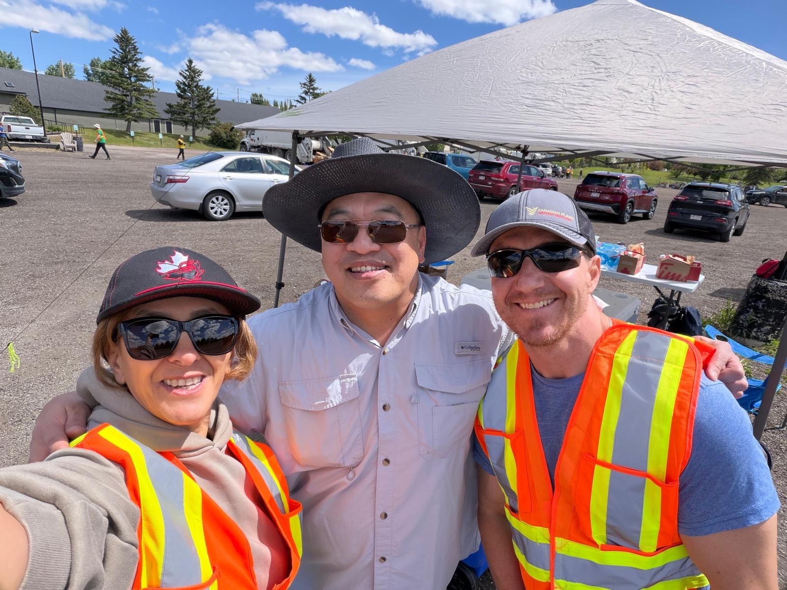 The three cleanup organizers — Behrokh, Kiel, and Rob — smiling under the volunteer tent.