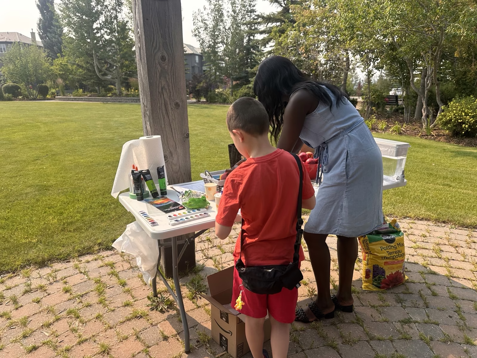 A young participant choosing colours at the supply table set up beside the gazebo