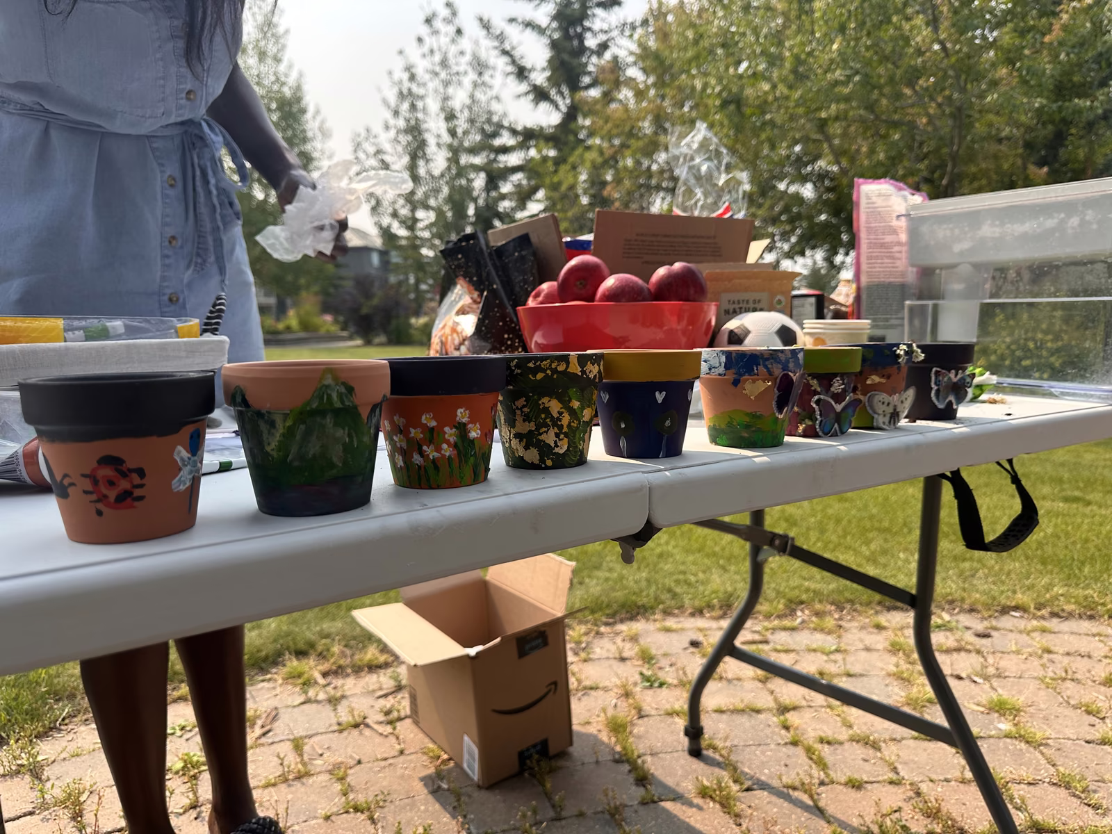A row of finished hand-painted terracotta pots lined up along the table, each one decorated differently