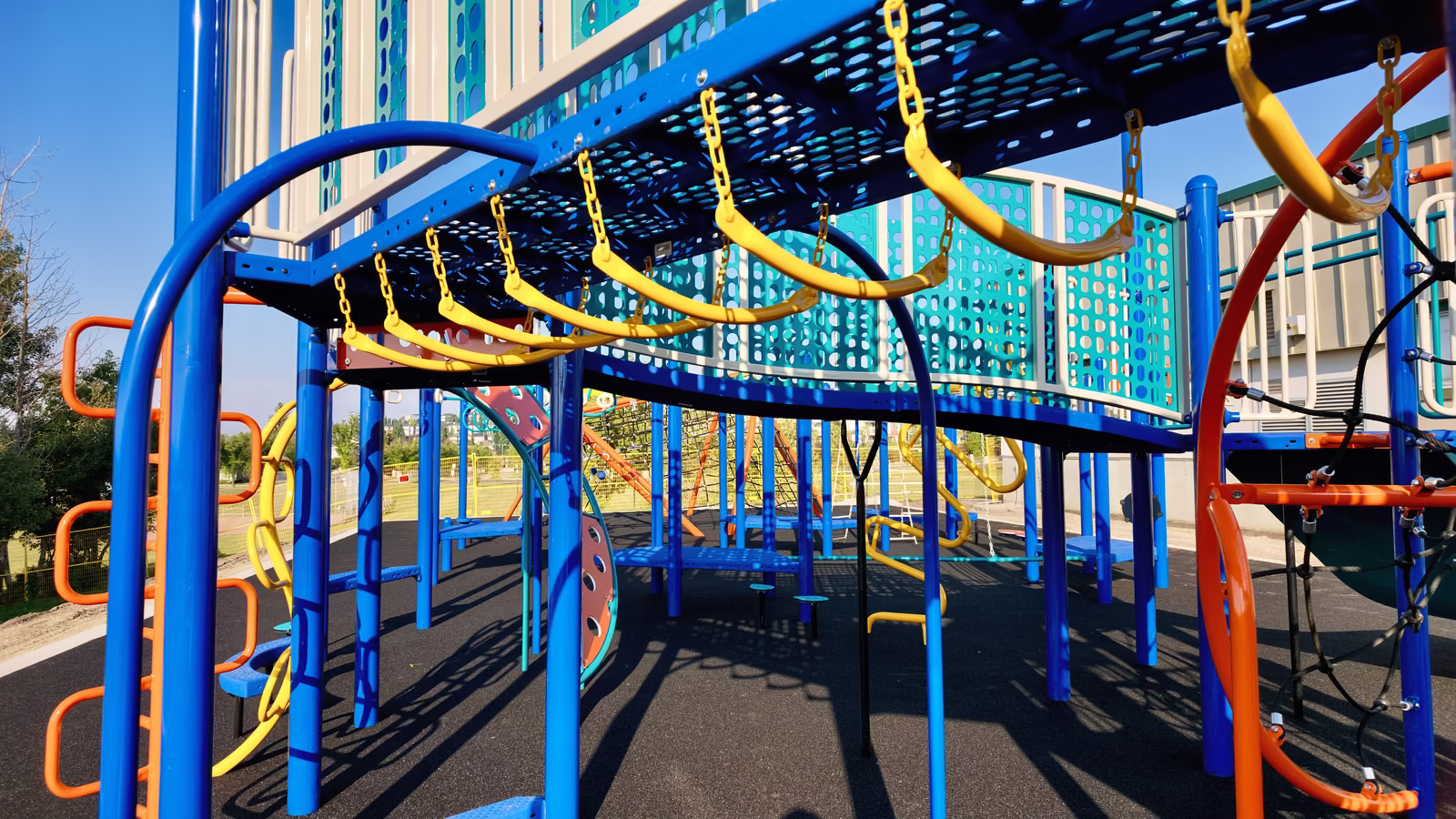 A long row of yellow and teal overhead swinging rings running the length of the structure