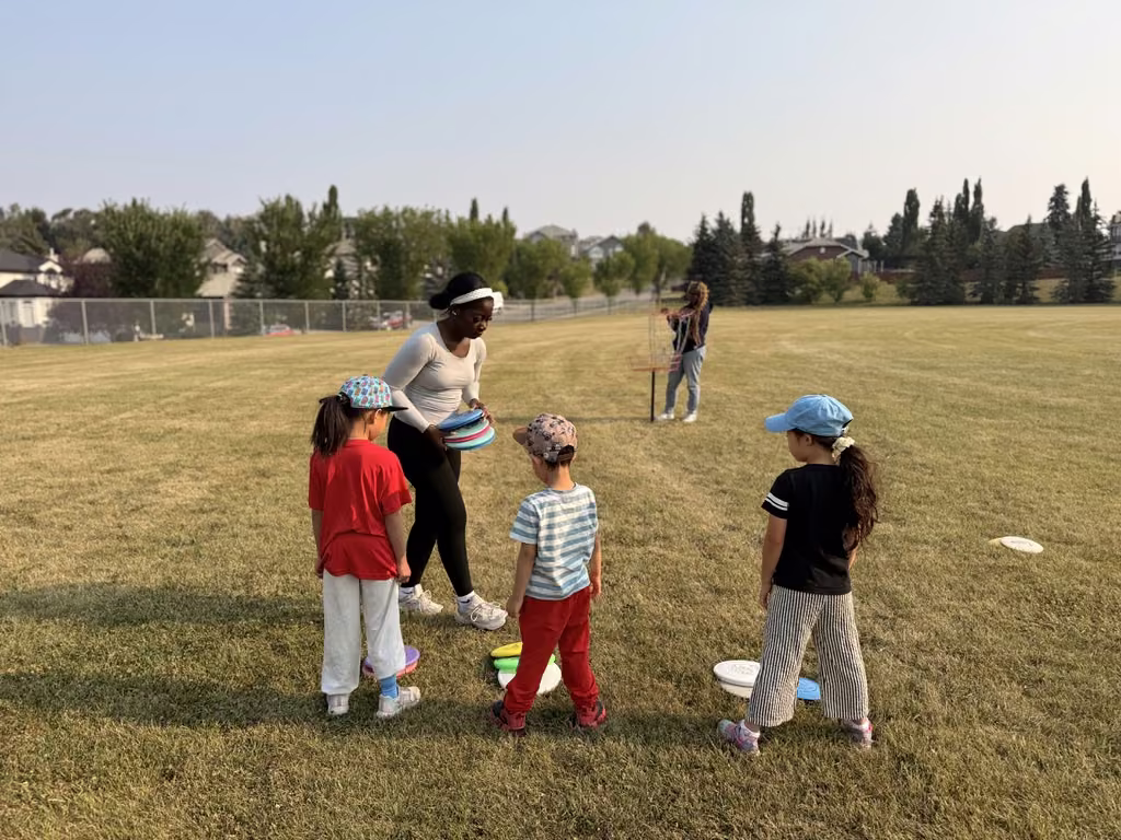 A coach handing out colourful discs to young participants at the start of the session