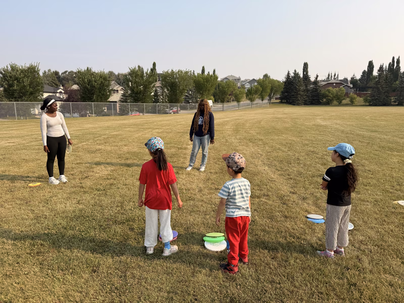 Kids and coaches in a warm-up circle on the field, practising their first throws
