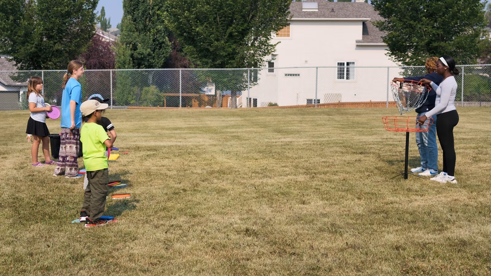 Kids lining up shots at the chain basket while a coach steadies it