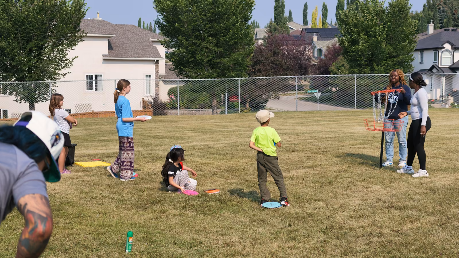 A young player mid-throw aiming at the disc golf basket